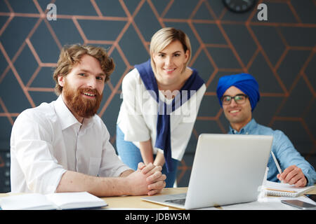 Drei junge multi-ethnischen Spezialisten Blick in die Kamera Stockfoto