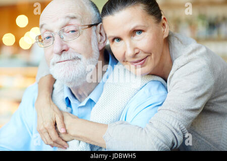 Reife Frauen umarmte ihren Mann und beide Blick in die Kamera Stockfoto