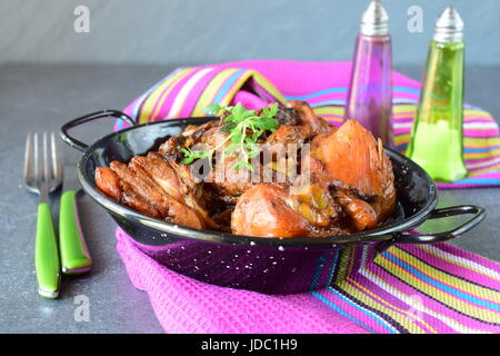 Huhn mit Pflaumen gekocht im Ofen in einer schwarzen Schale auf textilen Untergrund. Stockfoto