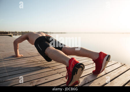 Porträt eines gesunden jungen Mannes tun Push Ups am Strand am Morgen Stockfoto