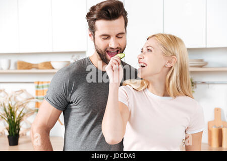 Foto von lustige junge liebende Paar stehen an Küche und kochen zusammen. Auf der Suche zur Seite. Stockfoto