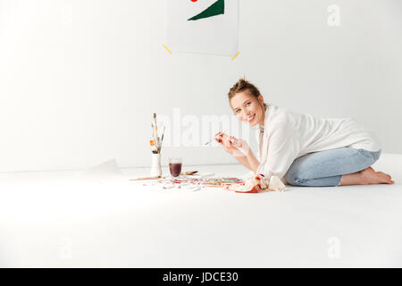 Bild des Malers glücklich kaukasischen Fräulein Arbeitsbereich. Blick in die Kamera. Stockfoto