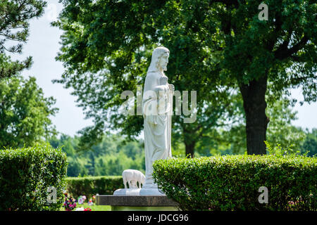 Eine Statue von Jesus Christus mit Lämmer montiert auf einem Friedhof in Wichita, Kansas, USA an einem Frühlingsmorgen. Stockfoto