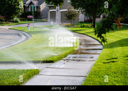 Ein im Boden sprinkler-System neben einem Bürgersteig liefert Wasser zu einem städtischen Rasen in Wichita, Kansas, USA. Stockfoto