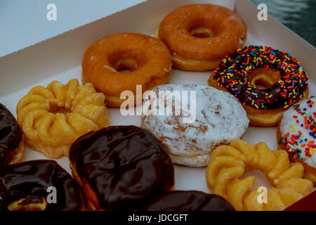 Bunte Donuts in Box auf Holztisch. Ansicht von oben mit Stockfoto