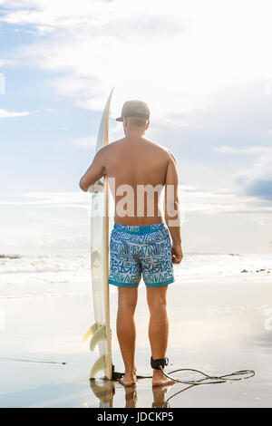 Nahaufnahme von gutaussehenden Mann Stand mit Surf Board bei Surfspot am Meer Ocean Beach und warten auf die Welle. Blick von hinten. Konzept des Sports, Freiheit, happin Stockfoto