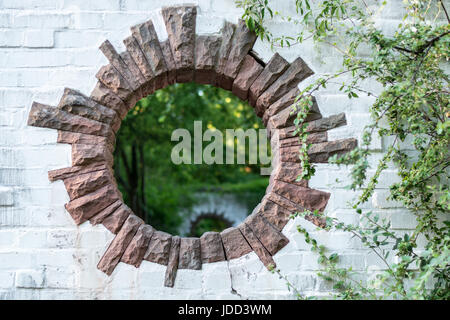 Ein rundes Loch in einer Mauer in einem Park sieht aus wie ein Portal in eine andere dimension Stockfoto