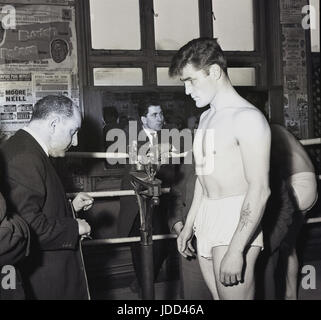 1959, die Turnhalle an der berühmten Thomas A Beckett Public House auf der Old Kent Road, Bermondsey, Süd-London, SE1, England, zeigt Bild einen Boxer stehen in einem Ring wird offiziell gewogen. Stockfoto