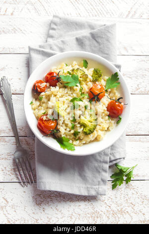 Bulgur mit Gemüse: Tomaten, Brokkoli und Petersilie auf weißem Holz Hintergrund - gesunde hausgemachte Bio Vegan vegetarische Ernährung Lebensmittel Stockfoto