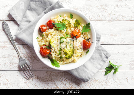 Bulgur mit Gemüse: Tomaten, Brokkoli und Petersilie auf weißem Holz Hintergrund - gesunde hausgemachte Bio Vegan vegetarische Ernährung Lebensmittel Stockfoto