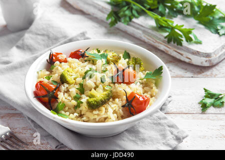 Bulgur mit Gemüse: Tomaten, Brokkoli und Petersilie auf weißem Holz Hintergrund - gesunde hausgemachte Bio Vegan vegetarische Ernährung Lebensmittel Stockfoto
