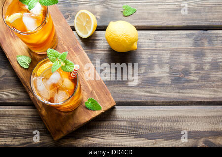 Eistee mit Zitrone, Minze und Eiswürfel auf hölzernen rustikalen Hintergrund hautnah. Hausgemachte erfrischendes Sommergetränk. Stockfoto