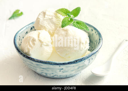 Vanille-Eis mit Minze in blauen Keramikschale. Hausgemachtes Eis, Textfreiraum. Stockfoto