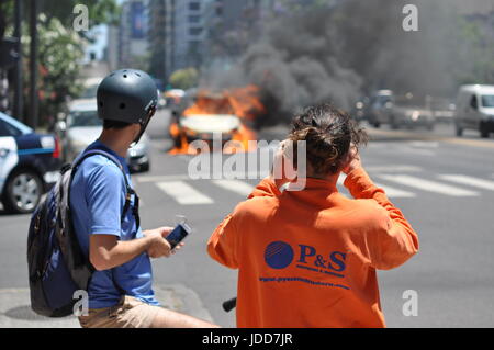 Zuschauer beobachten und Filmen von einem brennenden Auto mitten auf einer Straße in Belgrano, Buenos Aires Stockfoto