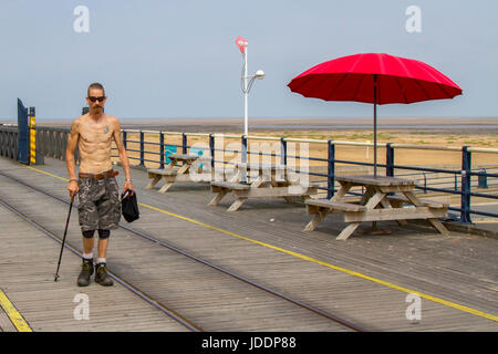 Holz- Picknick Tische & Stühle mit roten Sonnenschirme in Southport, Merseyside, UK. UK Wetter. 20 Juni, 2017. Leichte Winde und lückenhafte Wolken auf Southport Meer als pier Kinderwagen die Meeresbrise aus der Irischen See genießen. Vereinzelt Wolken geben etwas Entlastung von den hohen Temperaturen, als Urlauber und Touristen die Promenade die längste Eisen Pier in Großbritannien. Stockfoto