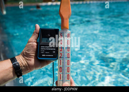 Ein Bademeister misst die Temperatur des Wassers, derzeit bei 24,3 Grad Celsius, in einem öffentlichen Freibad in Nürnberg, 20. Juni 2017. Ein anderes Thermostat zeigt die Luft-Temperatur von 34 Grad Celsius. Foto: Daniel Karmann/dpa Stockfoto