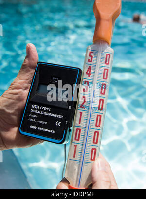 Ein Bademeister misst die Temperatur des Wassers, derzeit bei 24,3 Grad Celsius, in einem öffentlichen Freibad in Nürnberg, 20. Juni 2017. Ein anderes Thermostat zeigt die Luft-Temperatur von 34 Grad Celsius. Foto: Daniel Karmann/dpa Stockfoto