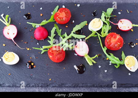 Gemischte Salat mit Radieschen, Wachteleier, Rucola und Cherry-Tomaten mit Balsamico-Glasur Stockfoto