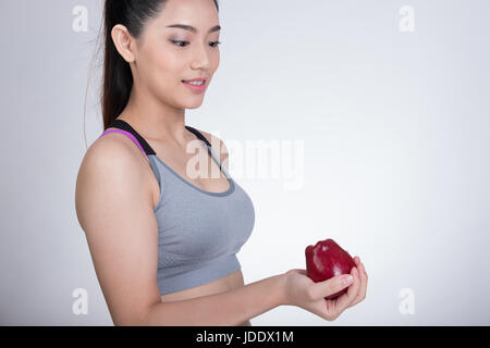 schöne gesunde sportlich sportlich Asiatin mit roten Apfel nach dem Training. attraktive lächelnde Frau vor weißem Hintergrund stehen. Stockfoto