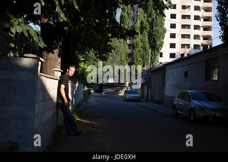 Person und Stadt. Ein Mann ist in der Nähe einer Wand auf der Straße stand. Stockfoto