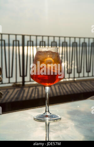 Kellner vorbereitet Aperol Sprits Sommer cocktail mit Aperol, prosecco, Eis-Würfel und Orange im Weinglas, bereit, auf der sonnigen Terrasse mit Meer zu trinken Stockfoto