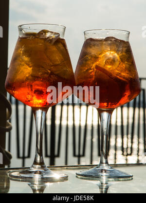 Kellner vorbereitet Aperol Sprits Sommer cocktail mit Aperol, prosecco, Eis-Würfel und Orange im Weinglas, bereit, auf der sonnigen Terrasse mit Meer zu trinken Stockfoto