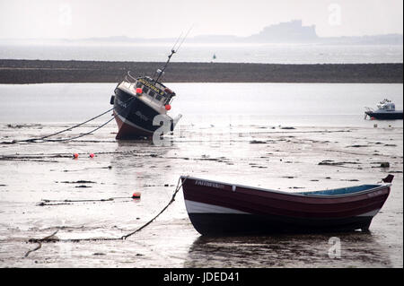 Boote von Heiligen Insel mit Bamburgh Castle im Hintergrund Stockfoto