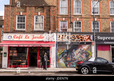 London, UK - Oktober 2016. Alter Mann vor klassischen britischen lokalen Cafè Feinkost genannt "Cafe Jardin" neben einem geschlossenen Haar Studio Shop. Stockfoto