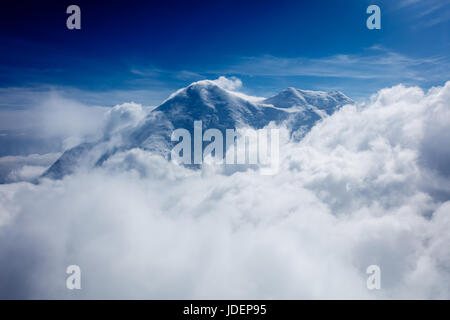 Luftaufnahme von oben Schnee begrenzt Gipfel eingehüllt in Wolken unter Stockfoto