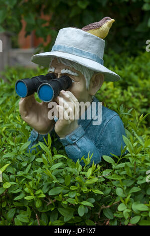 Figur mit Vogel am Hut und Fernglas über eine Hecke, Bayern, Deutschland Stockfoto