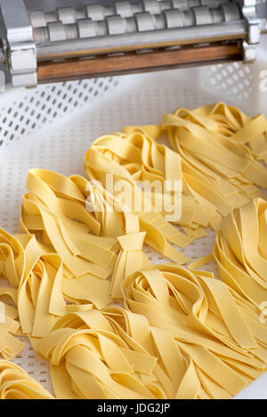 Frisch zubereitete Bänder des italienischen Tagliatelle Nudeln liegend in den Stapel in einen weißen Plastikschale im hohen Winkel Nahaufnahme Stockfoto