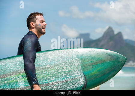 RIO DE JANEIRO - 10. Februar 2017: Brasilianische Surfer mit Surfbrett entlang des Ufers am Arpoador mit zwei Brüder Berg im Hintergrund geht Stockfoto