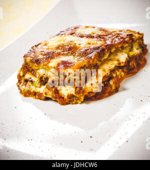 Lasagne Bolognese. Typische hausgemachte frische grüne Nudeln gekocht im Ofen. Ein Teil in der Platte. Stockfoto