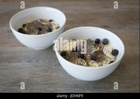 zwei Schüsseln Porridge mit Banane, Chia-Samen und Heidelbeeren Stockfoto