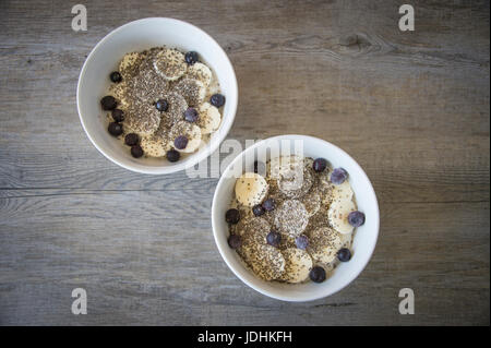 Zwei Schüsseln Porridge mit Banane, Chia-Samen und Heidelbeeren Stockfoto