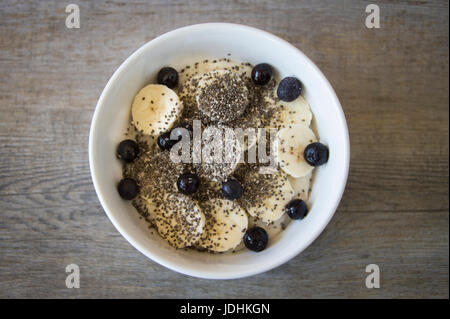 Schüssel Haferbrei mit Banane, Chia-Samen und Heidelbeeren, fotografiert von oben. Stockfoto