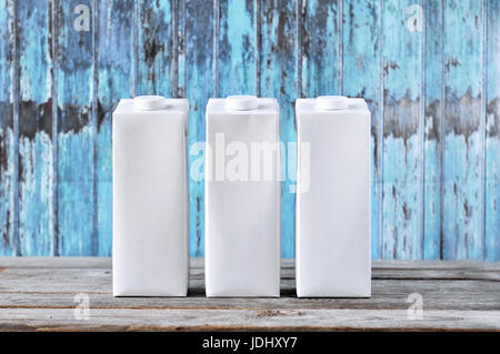 Tetra Pak ohne Muster auf blauem Grund. Rohe Kartonverpackung. Verpackungen für Flüssigkeiten. Stockfoto