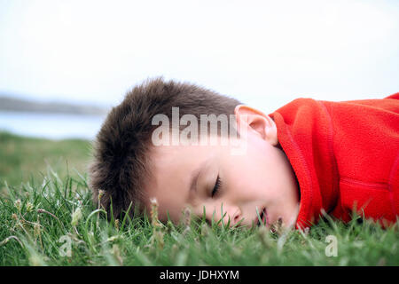 Jungen schlafen auf Rasen Stockfoto