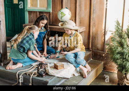 niedlichen Kinder spielen Schatzsuche mit Karte auf Veranda Stockfoto