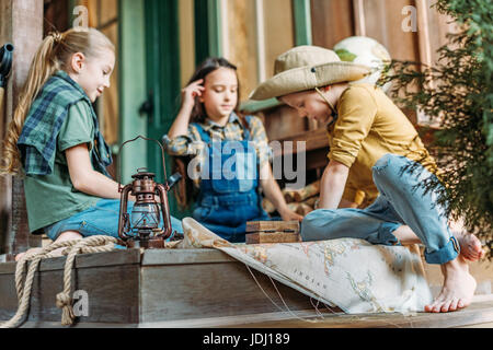 niedlichen Kinder spielen Schatzsuche mit Karte auf Veranda Stockfoto