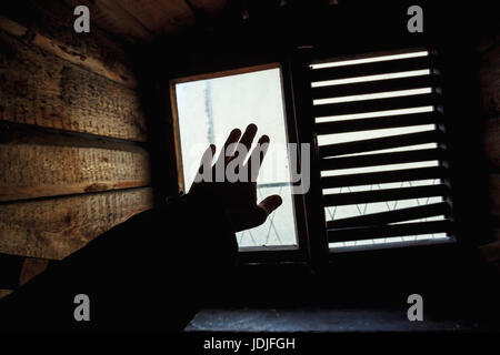 Männliche Hand Silhouette über kleine Grunge Fenster mit Fensterläden Stockfoto
