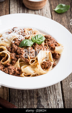 Pasta aus traditionellen italienischen Bandnudeln Bolognese mit Käse Grana Padana auf rustikalen Holztisch serviert Stockfoto