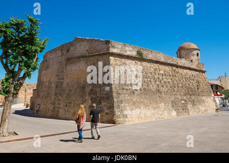 Gehen Sie Alghero Sardinien, ein paar Touristen vorbei an einem Abschnitt der Stadtmauer bekannt als der Bastione La Maddalena in der Altstadt von Alghero, Sardinien. Stockfoto