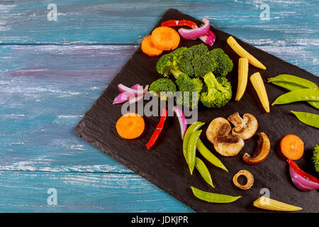 Vielzahl von grüne Rohkost Salate, Salat, Chinakohl, Mais, Brokkoli, Wirsing, bunten jungen Karotten und Blumenkohl über den schwarzen Stein text Stockfoto