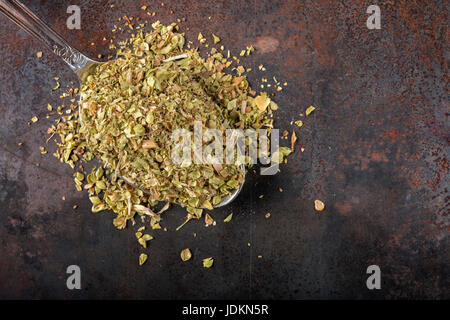 Löffel gefüllt mit getrockneten Oregano auf rostigen Hintergrund mit Textfreiraum Stockfoto