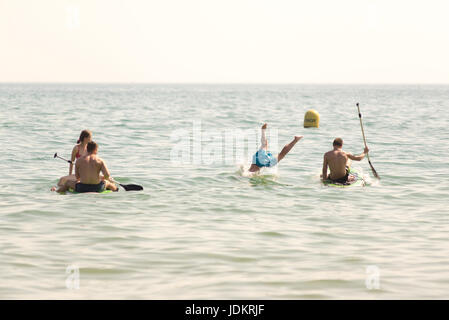 Boscombe Beach, Bournemouth, Dorset, Großbritannien, 20.. Juni 2017. Leute, die Spaß auf Paddleboards haben, ein Mann mit seinen Beinen in der Luft, der von einem Paddleboard eintaucht. Die längste Juni-Hitzewelle seit über 20 Jahren und das heiße Wetter erhöhten die Temperatur an der Südküste fast auf 30 Grad. Stockfoto