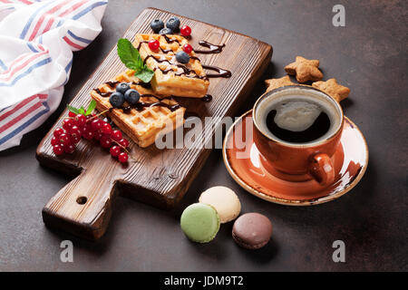 Süßigkeiten, Kaffee und Waffeln mit Beeren auf Schneidebrett Stockfoto