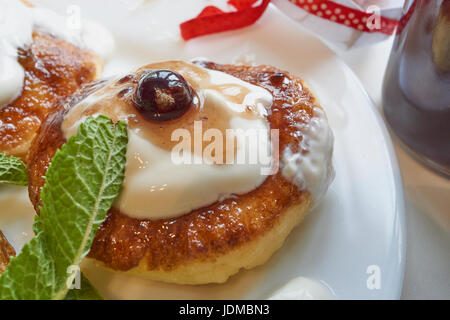 Quark Quark Pfannkuchen auf weisse Platte mit Rosinen, Minze und Johannisbeere Beeren. Nahaufnahme Makroaufnahme Stockfoto