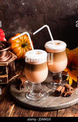 Zwei Gläser Kürbis würzig Latte mit Sahne und Zimt auf einem Holzständer Stockfoto