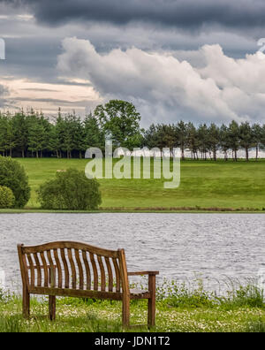 Piperdam See in Schottland mit den Bäumen und Hügeln in der Ferne. Es gibt auch ein isolierte Stuhl im Bild Blick auf den See. Stockfoto